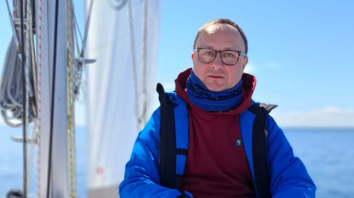 zdjęcie przedstawia mężczyznę w okularach i szaliku