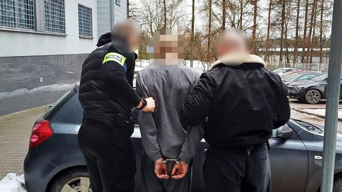 zdjęcie przedstawia mężczyznę z kajdankach prowadzonego przez innych mężczyzn