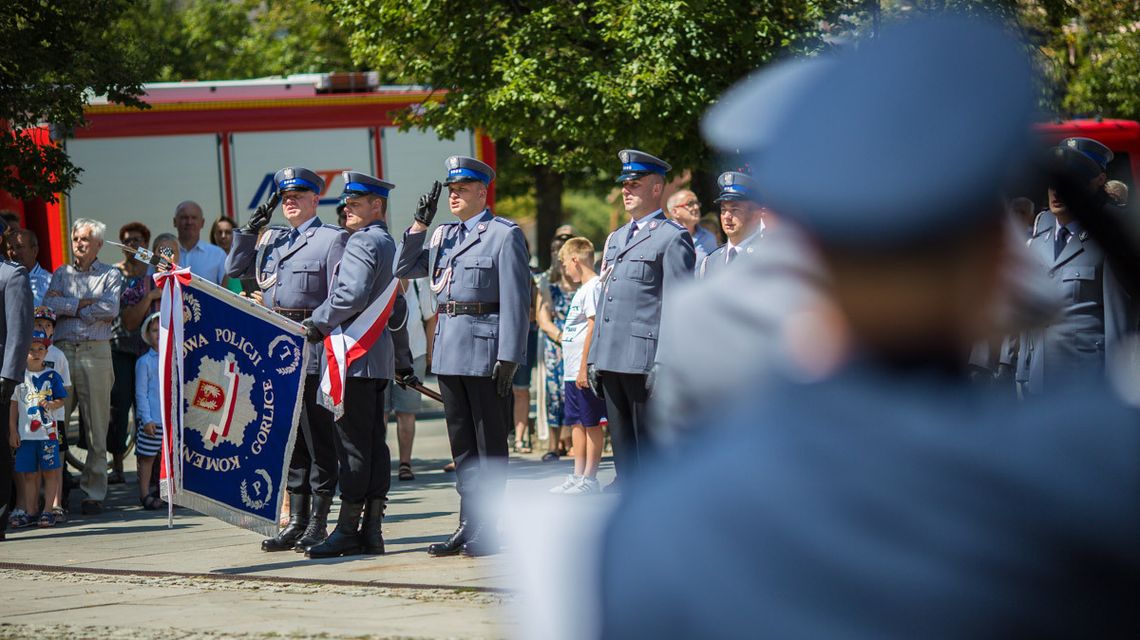 policjanci trzymający sztandar i salutujący podczas śpiewania hymnu