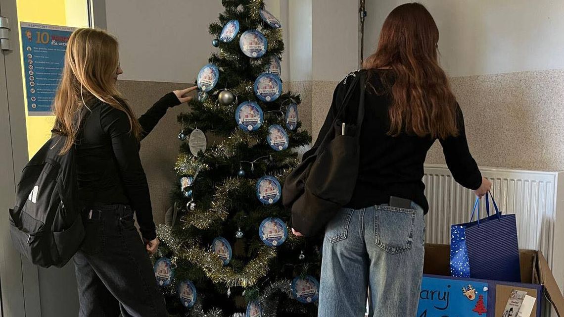 zdjęcie przedstawia choinkę, przed którą stoją dwie dziewczyny