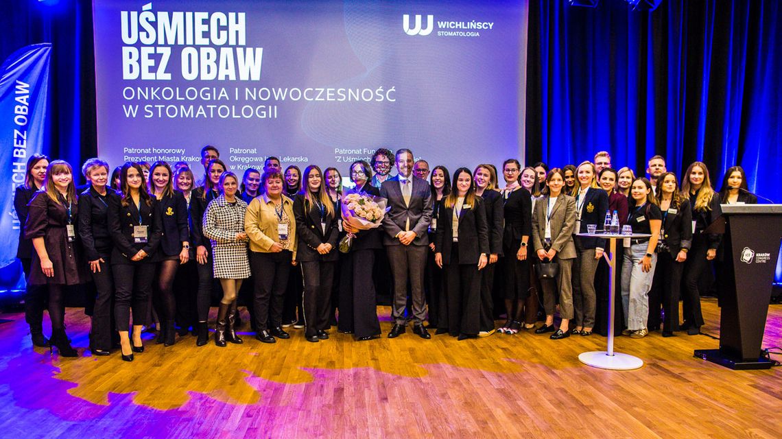 zdjęcie przedstawia grupę osób przed ekranem