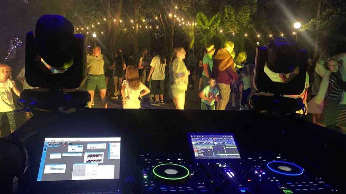 zdjęcie przedstawia tańczących ludzi w tle konsola dj-a