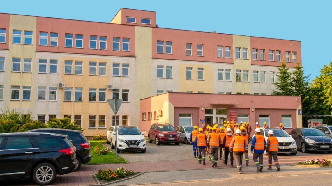 Powiat gorlicki z największym wzrostem bezrobocia w Małopolsce zdjęcie przedstawia robotników w kaskach idących w kierunku dużego budynku