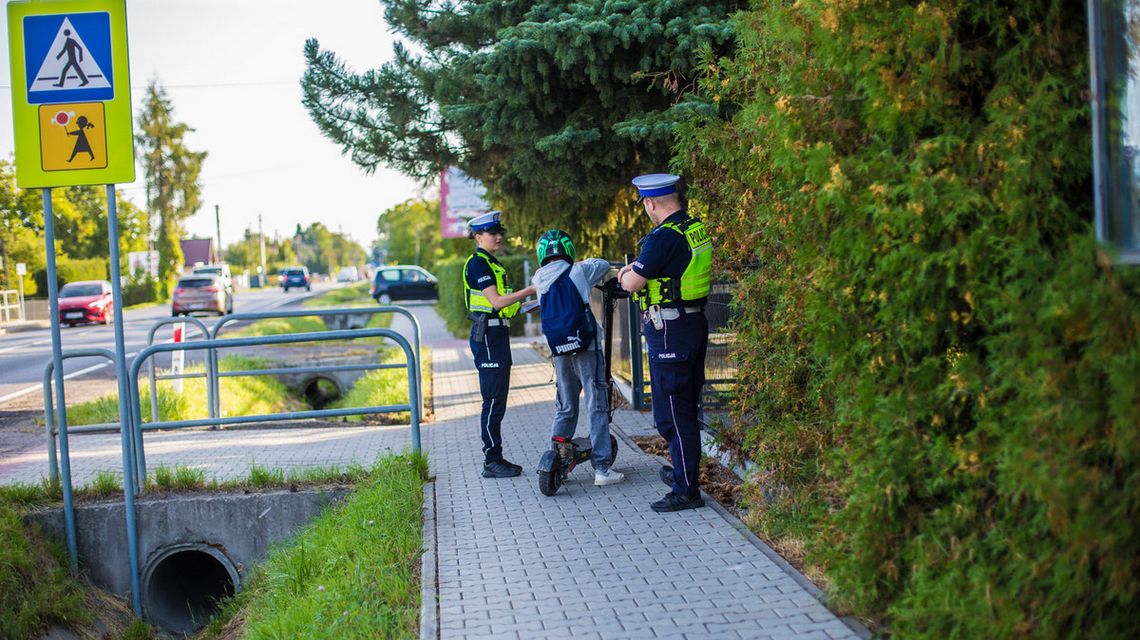 policjanci rozmawiają z chłopakiem, który przyjechał do szkoły na hulajnodze