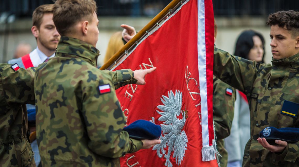 zdjęcie przedstawia młodego żołnierza wskazującego na sztandar podczas przysięgi na gorlickim Rynku
