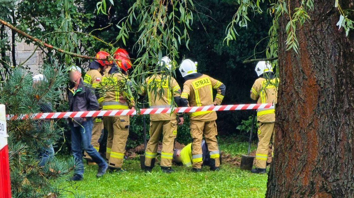 strażacy nad wykopem w którym pracuje mężczyzna