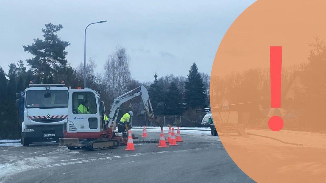 Zdjęcie przedstawia koparkę i samochód ciężarowy na jezdni, pracowników w żółtych kamizelkach