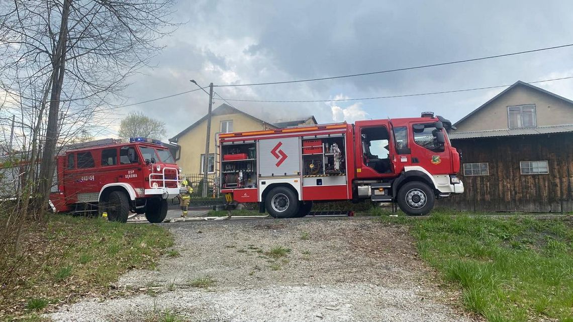 zdjęcie przedstawia wozy straży pożarnej przed domem z którego wydobywa się dym