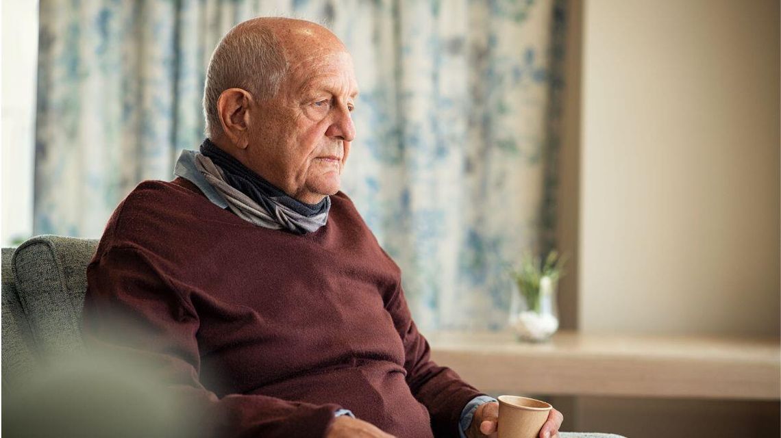 zdjęcie przedstawia starszego mężczyznę siedzącego na fotelu w domu