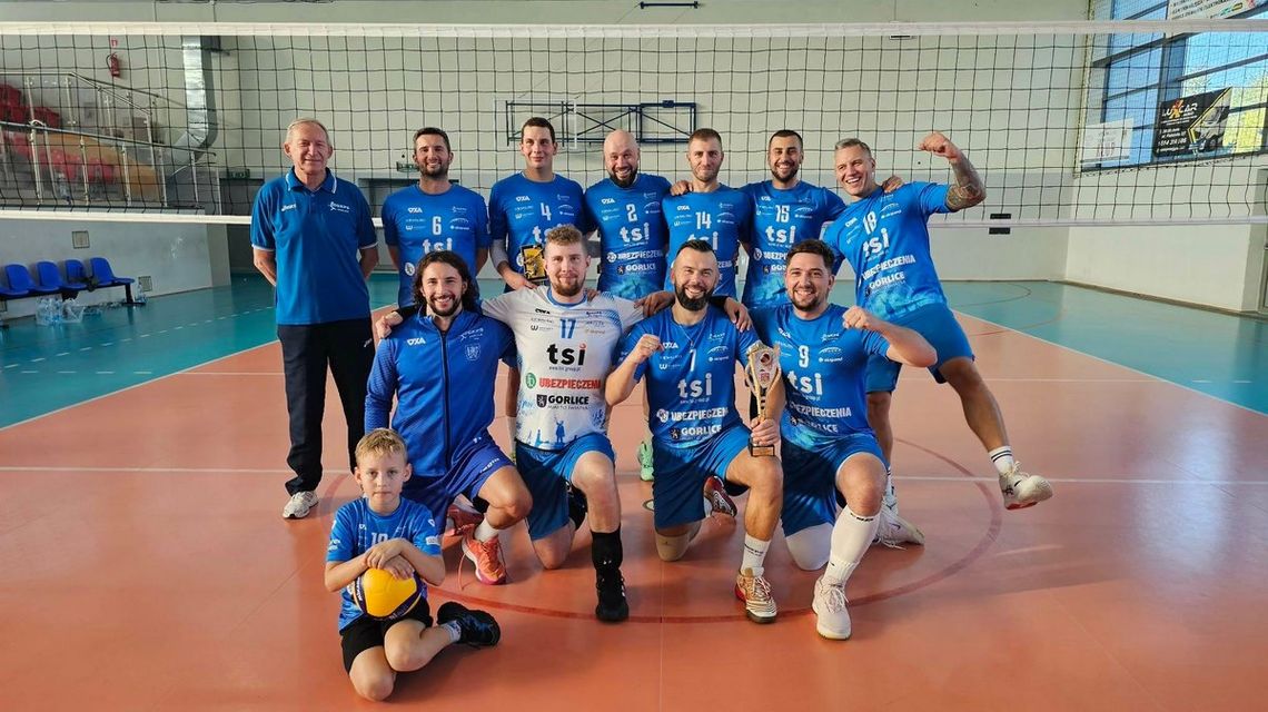 grupa sportowców w jednakowych strojach w hali sportowej, w tle siatka