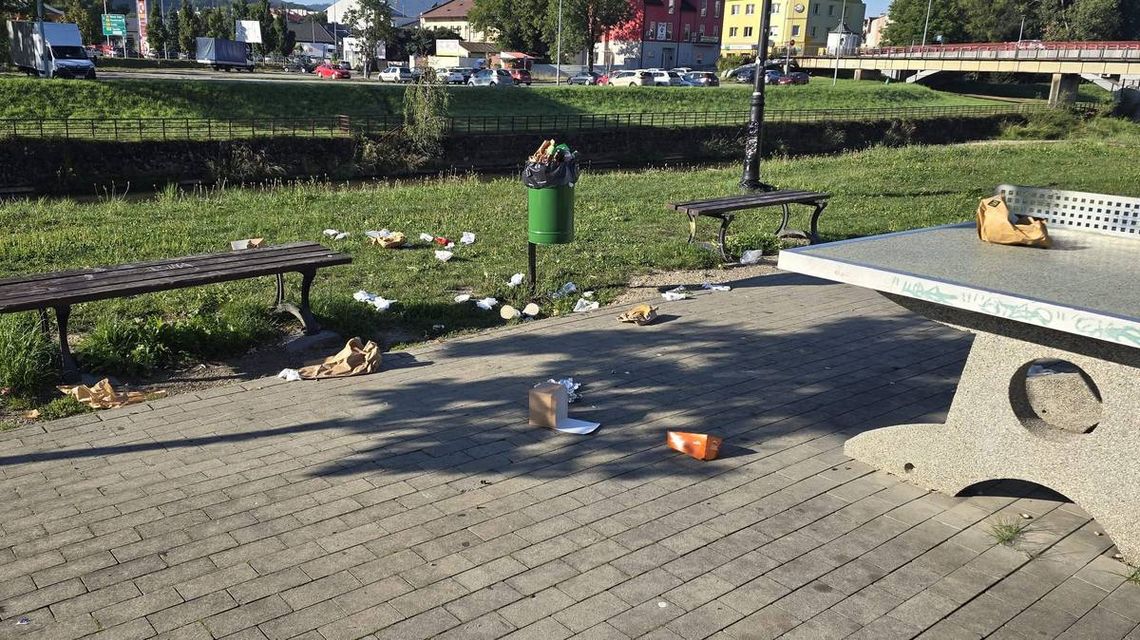 rozrzucone papierowe torebki, kubki przy ławce