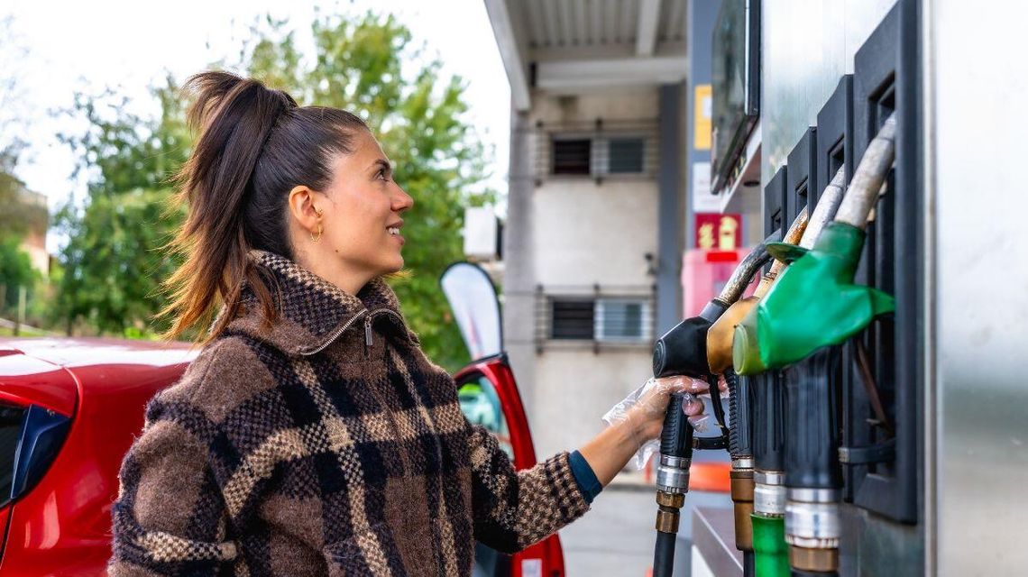 zdjęcie przedstawia kobietę chwytającą pistolet do tankowania, kobieta uśmiecha się