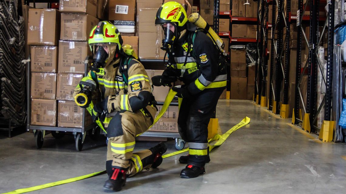 zdjęcie przedstawia dwóch strażaków w aparatach ochrony dróg oddechowych