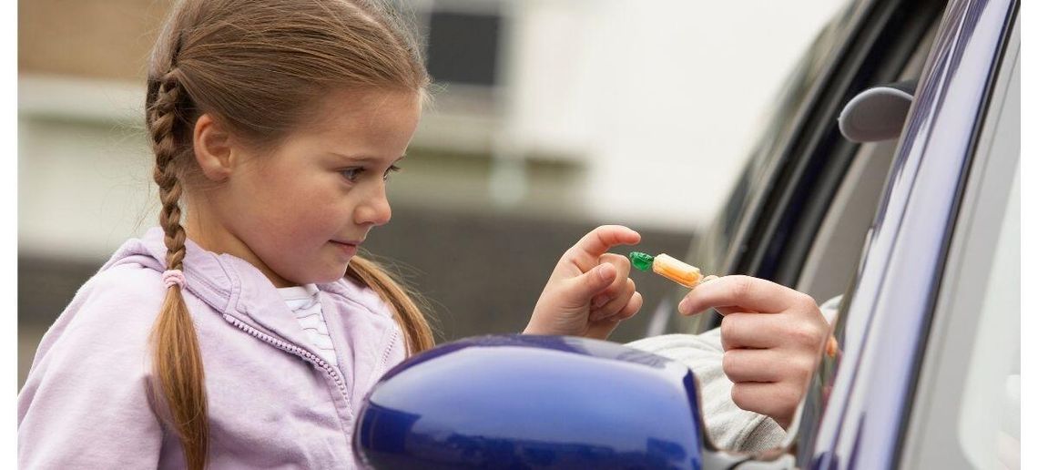 zdjęcie przedstawia dziewczynkę zabierającą cukierka