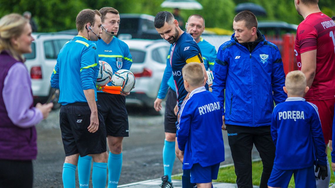 piłkarze przygotowujący się do meczu obok sędziowie i dziecięca eskorta