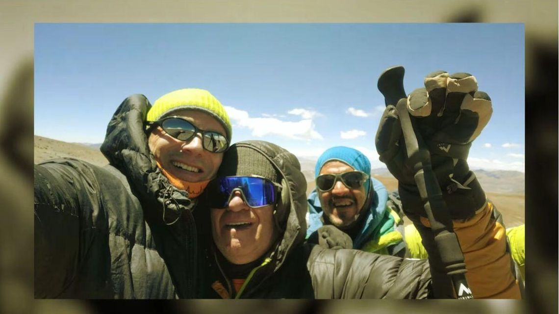 zdjęcie przedstawia mężczyzn z puchowych kurtkach na szczycie góry