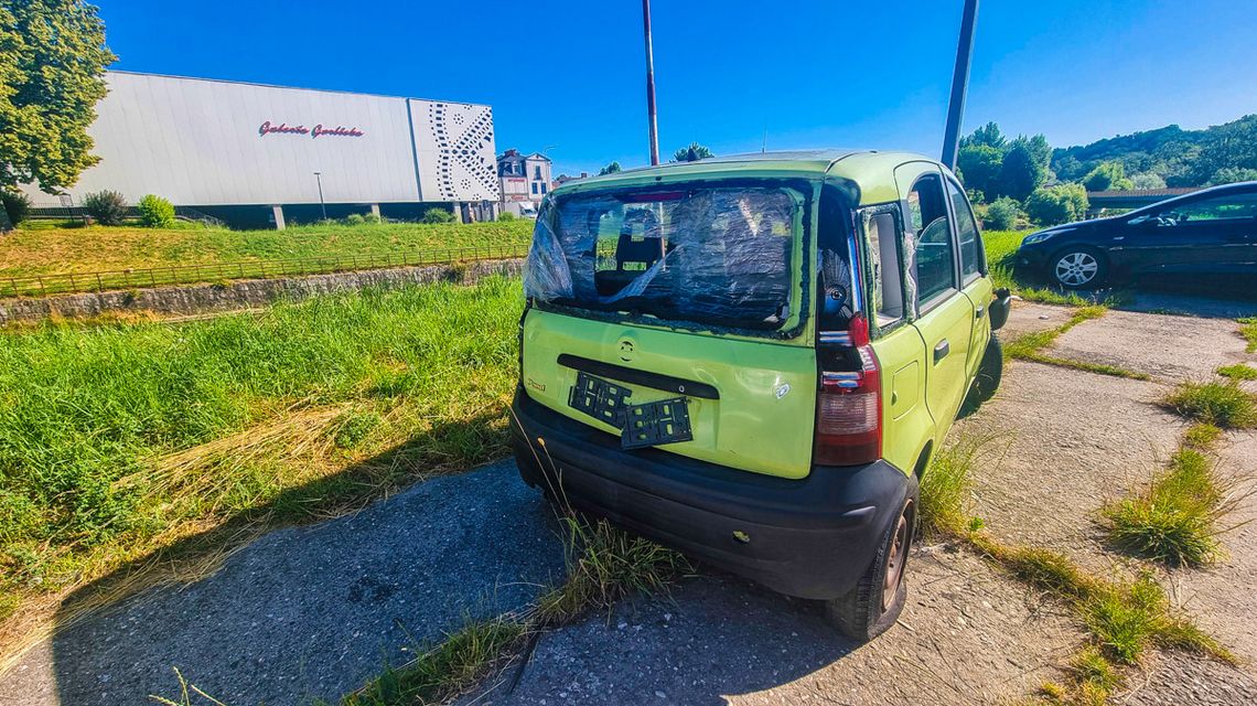 zdjęcie przedstawia zdezelowany samochód stojący na parkingu