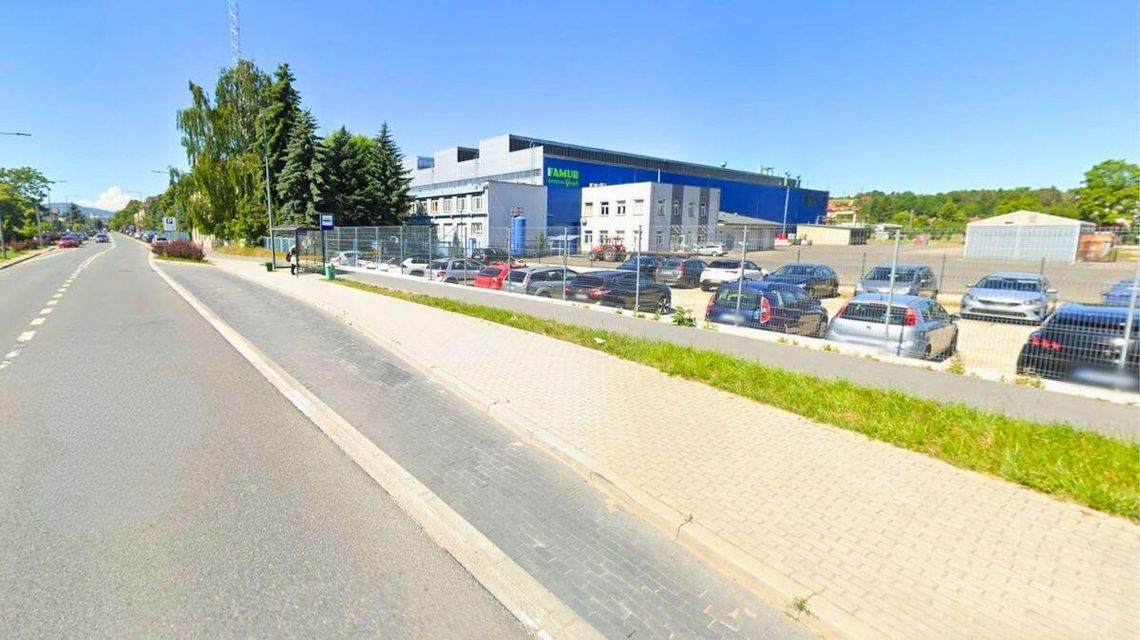 To już fakt. Famur zwolni 180 osób. Miasto chce pomóc pracownikom zdjęcie przedstawia dużą halę przy ulicy, obok parking