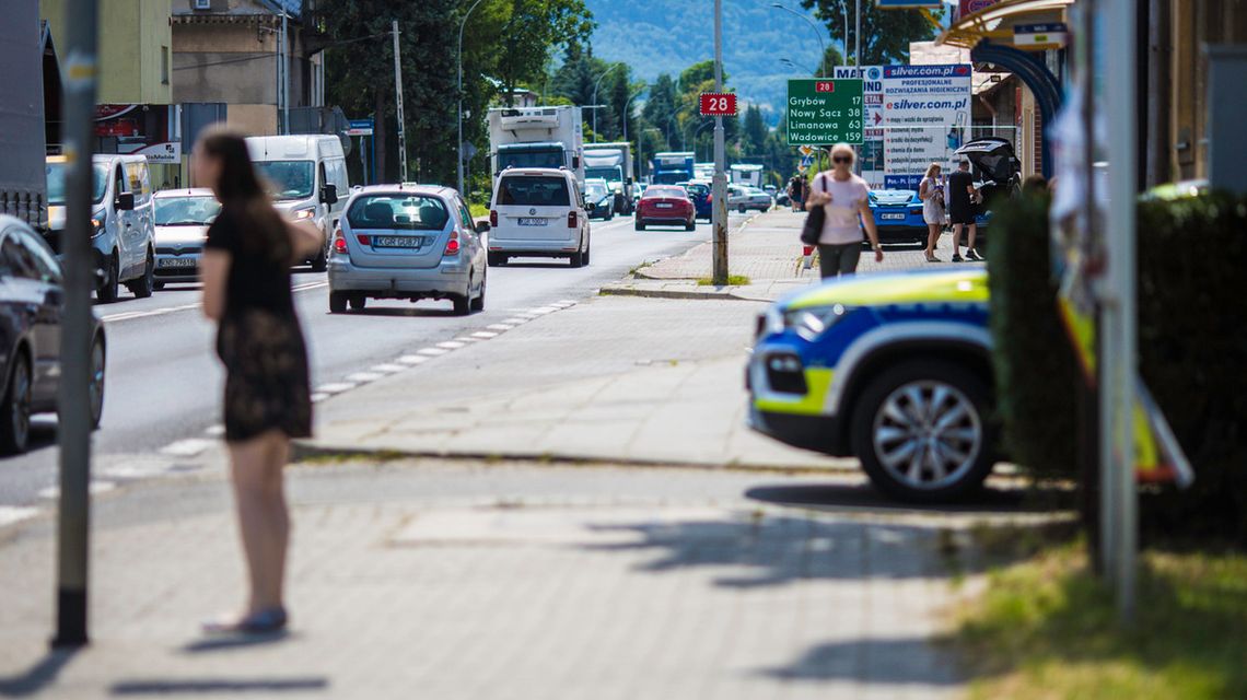 zdjęcie przedstawia jadące drogą samochody obok patrol policji