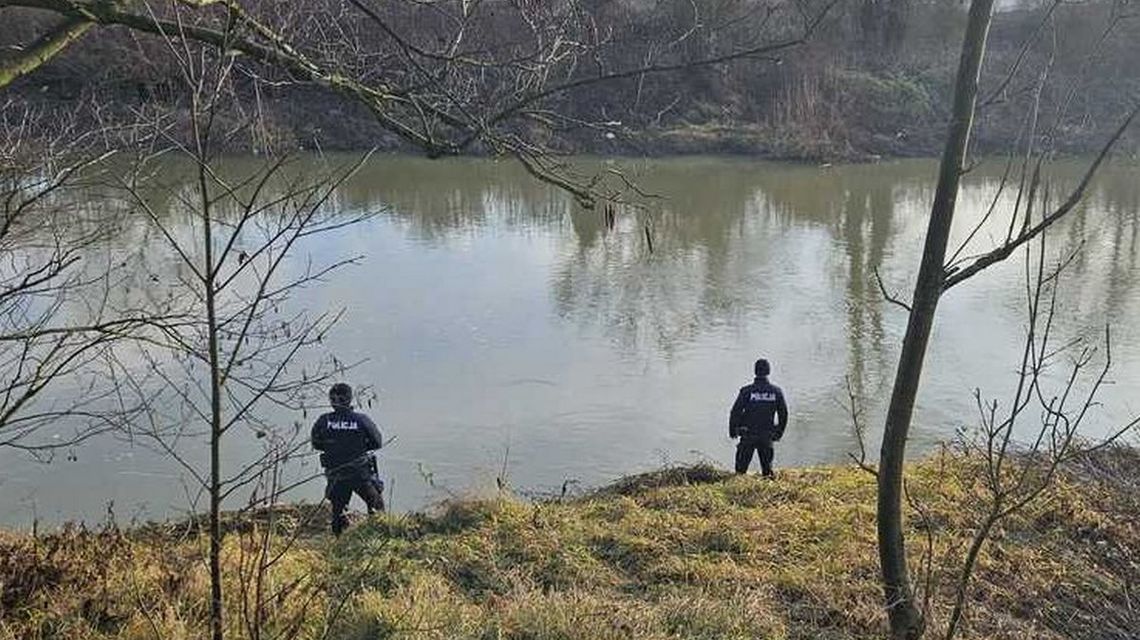 Tragiczny finał poszukiwań 57-letniej kobiety zdjęcie przedstawia dwóch policjantów stojących na brzegu rzeki