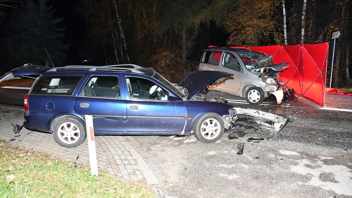 zdjęcie przedstawia rozbite pojazdy stojące na jezdni, obok jednego czerwony parawan