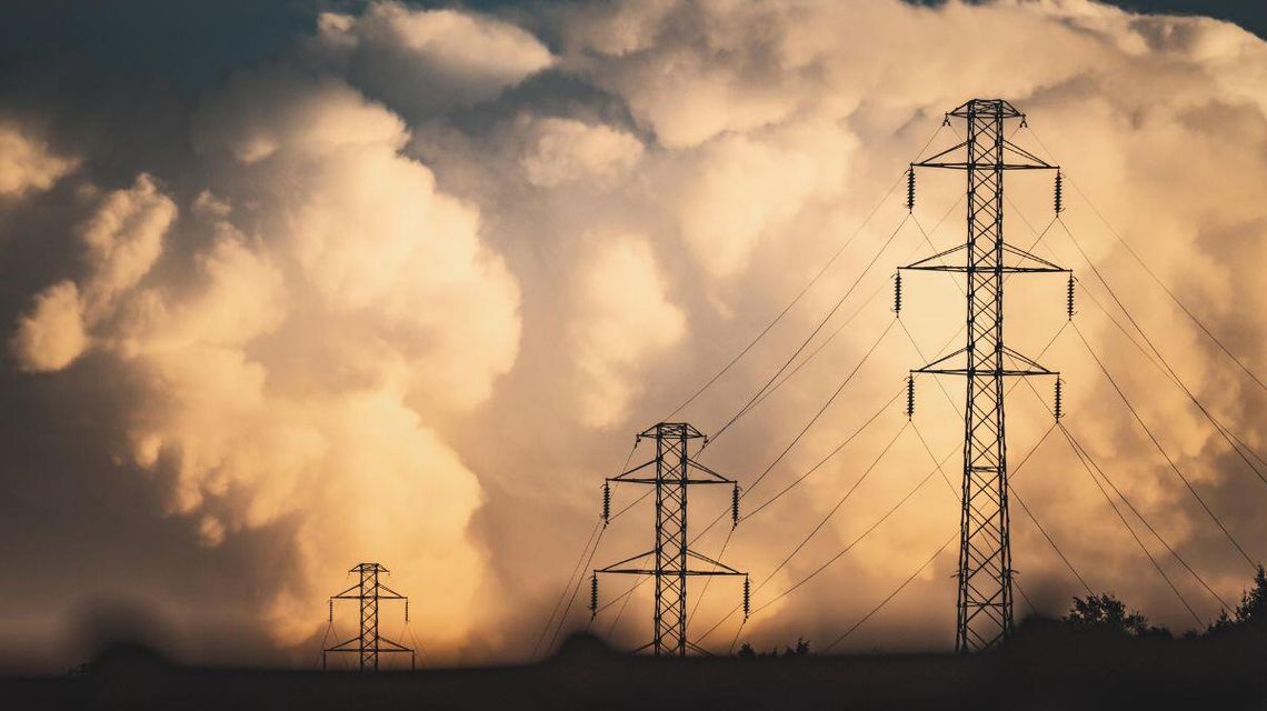 zdjęcie przedstawia słup energetyczny w tle chmury