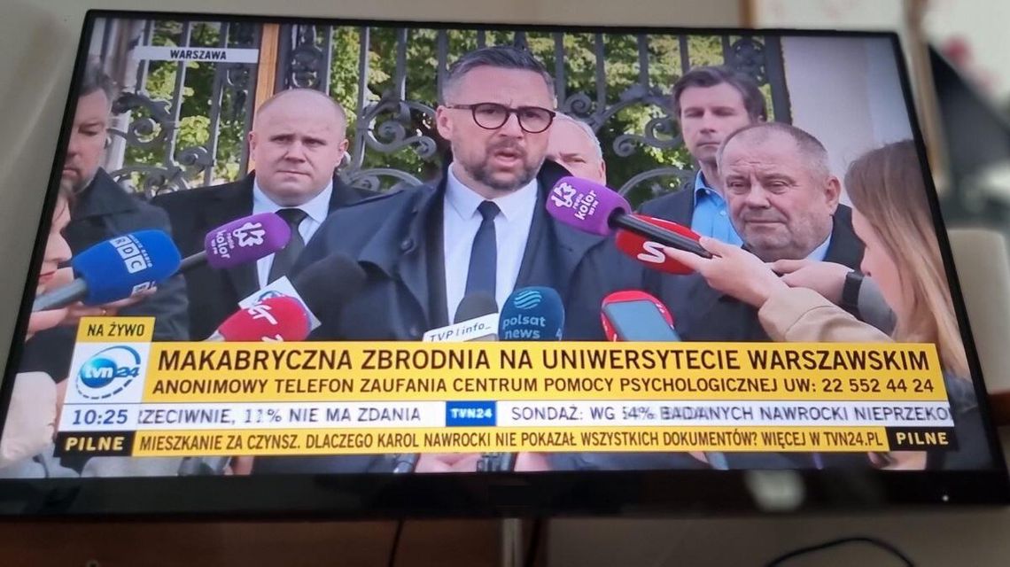 zdjęcie przedstawia monitor komputera na którym wyświetlany jest obraz pokazujący kilku mężczyzn podczas konferencji prasowej