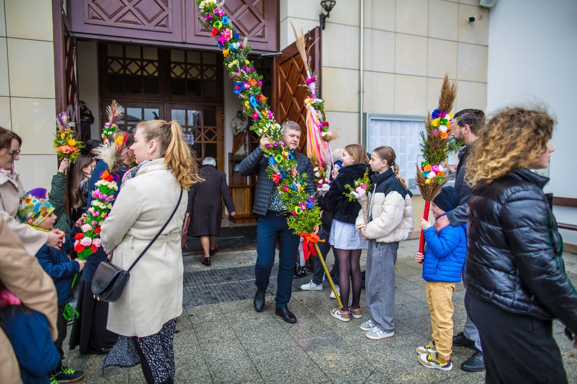 zdjęcie przedstawia mężczyznę wynoszącego palmę wielkanocną z kościoła