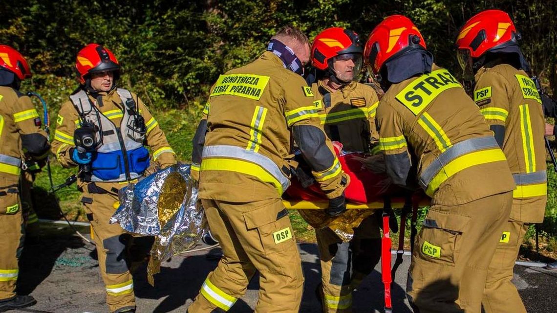 zdjęcie przedstawia strażaków niosących rannego na noszach