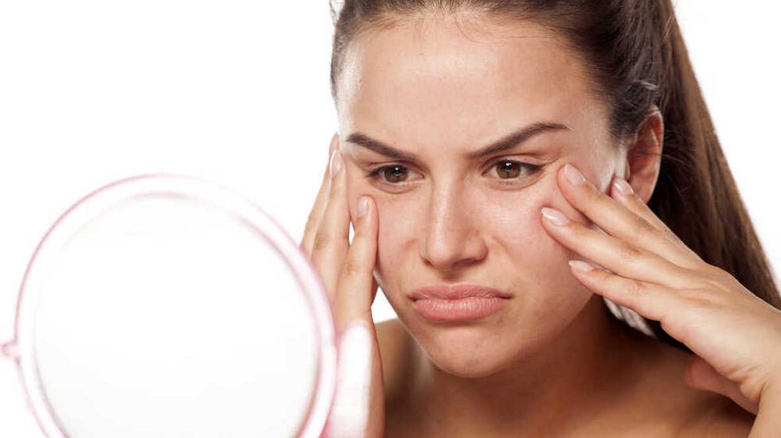 W jaki sposób skóra sygnalizuje problemy hormonalne zdjęcie przedstawia twarz kobiety, która się krzywi przed lusterkiem