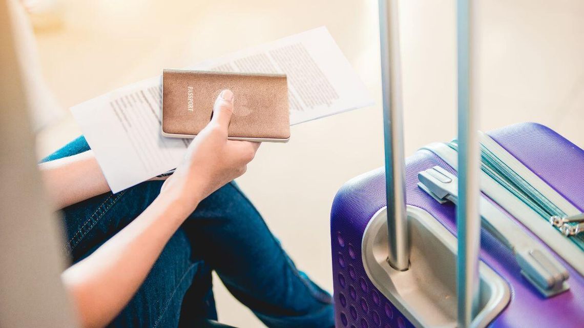 Wakacje na Melediwach skończyły się wcześniej, niż się nawet zaczęły zdjęcie przedstawia paszport trzymany w dłoni, obok walizka na lotnisku