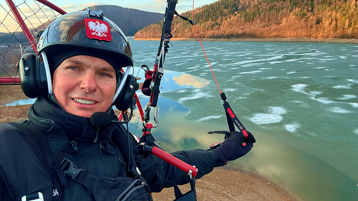 zdjęcie przedstawia mężczyznę w kasku na motoparalotni