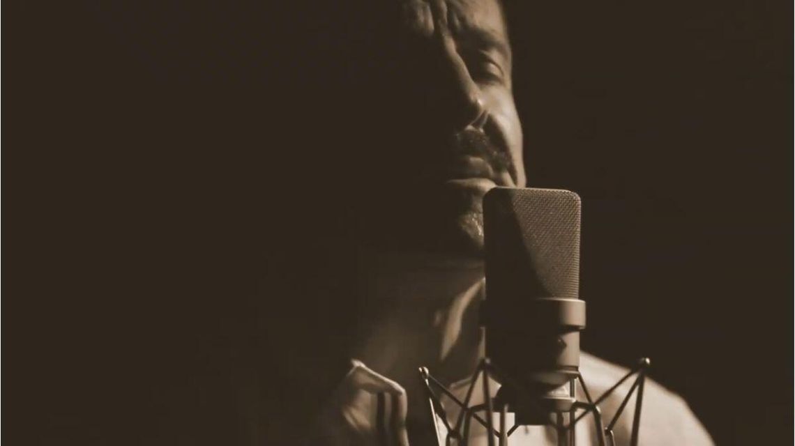 zdjęcie przedstawia mężczyznę przed mikrofonem