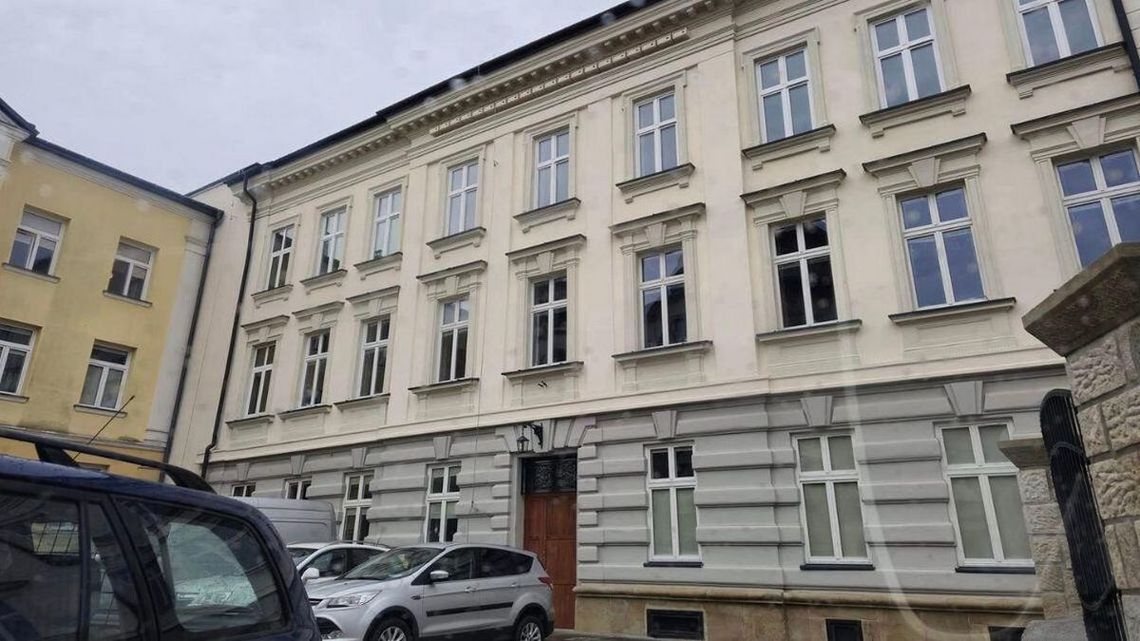 zdjęcie przedstawia budynek w mieście, przed którym stoją samochody