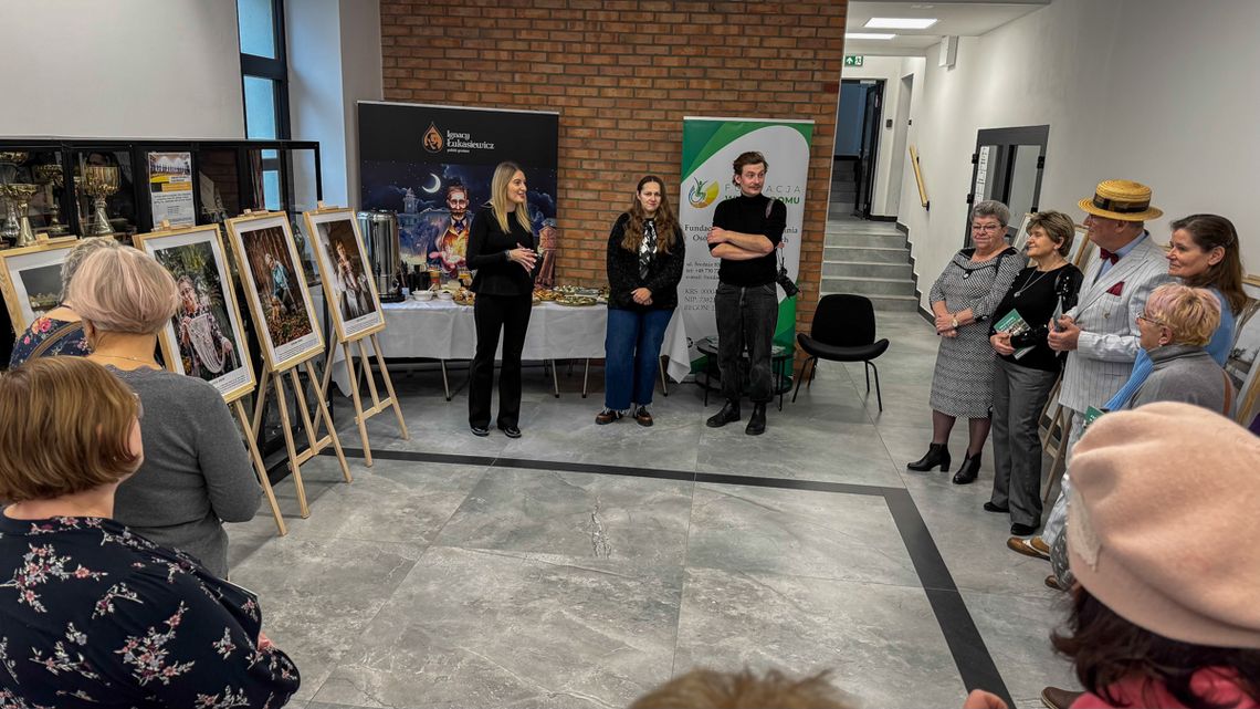 zdjęcie przedstawia kilka osób w pomieszczeniu wypełnionym portretami na sztalugach