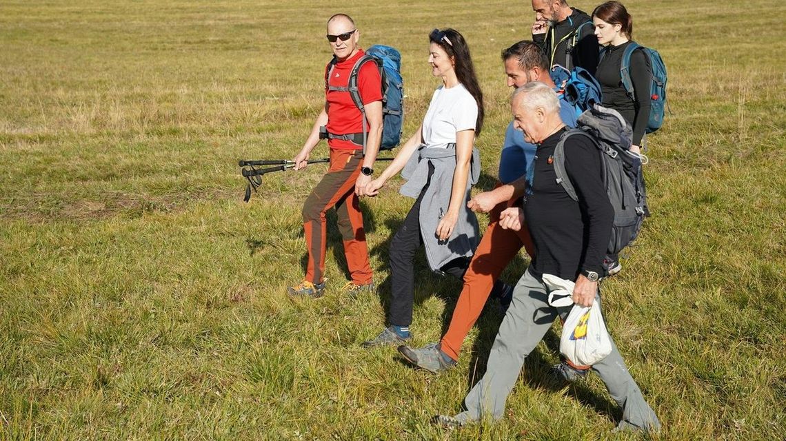 grupa osób idąca po polanie