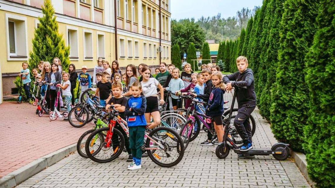 Uczniowie na rowerach przed szkołą