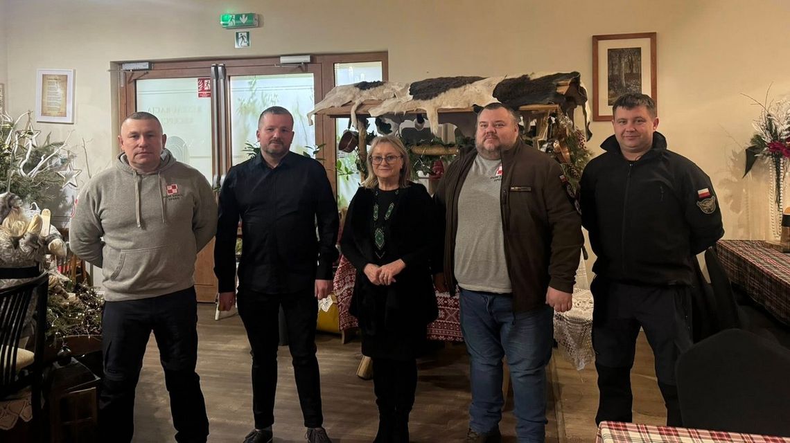 zdjęcie przedstawia kilku mężczyzn i kobietę pozujących do zdjęcia w pomieszczeniu