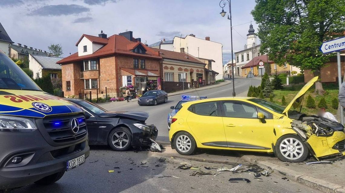 zdjęcie przedstawia zniszczone karoserie pojazdów obok dwie kobiety i mężczyzna