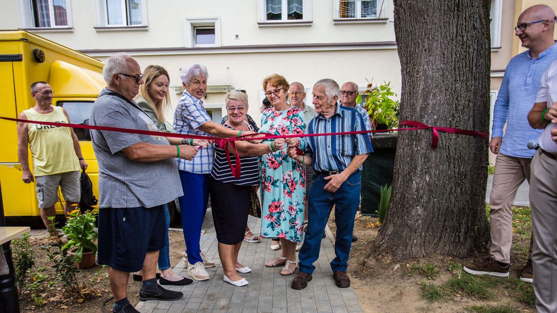 kilka starszych osób pociąga za czerwoną wstążkę, symbolizującą otwarcie mini parku w gorlicach