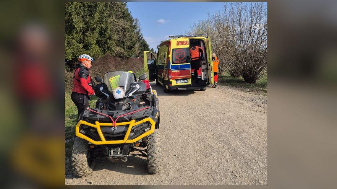 zdjęcie przedstawia ratownika na quadzie, obok stoi karetka pogotowia