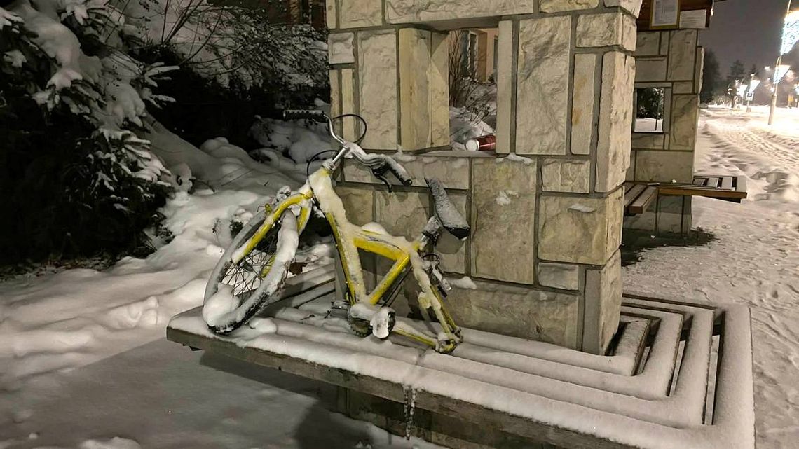 zdjęcie przedstawia żółtą ramę roweru z kołem leżącą na ławce przystanku