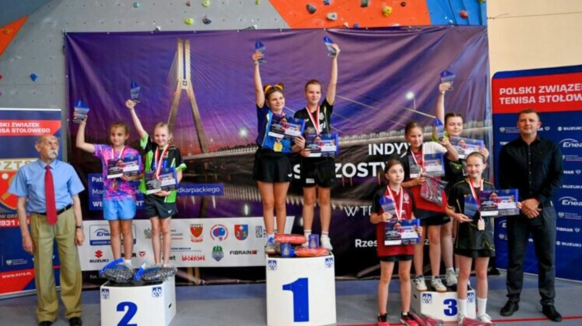 Młodzi sportowcy na podium z medalami.