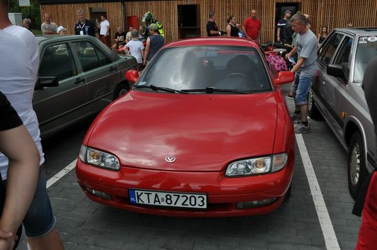 samochody i motocykle i ich kierowcy biorący udział w zlocie samochodowym